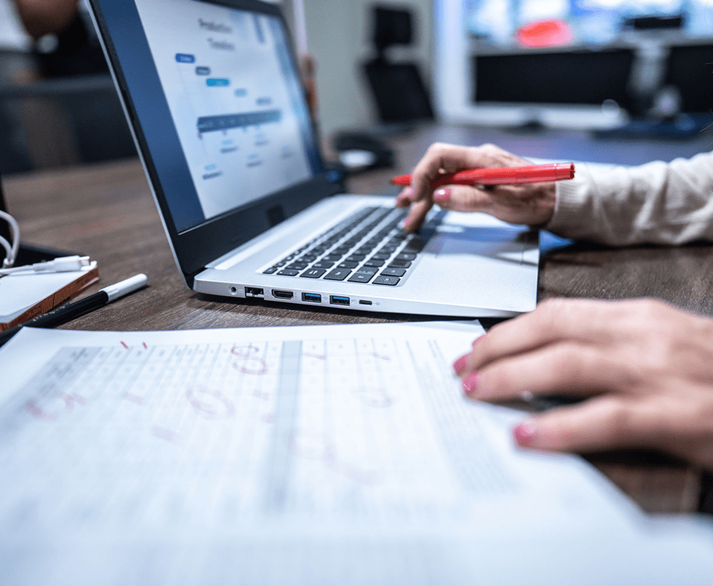 Person working on laptop with documents.